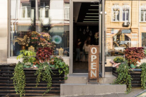 open signboard potted plants and reflecting windows at flower shop