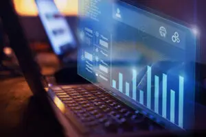 Futuristic holographic data dashboard projecting charts and icons over a laptop keyboard.