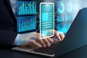 Person typing on a laptop while translucent blue data dashboards with charts float around the screen