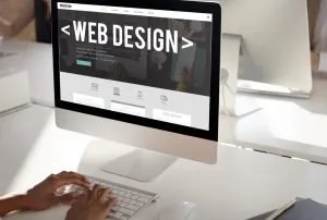 Monitor displaying a web design mockup with the words 'WEB DESIGN' on the screen.