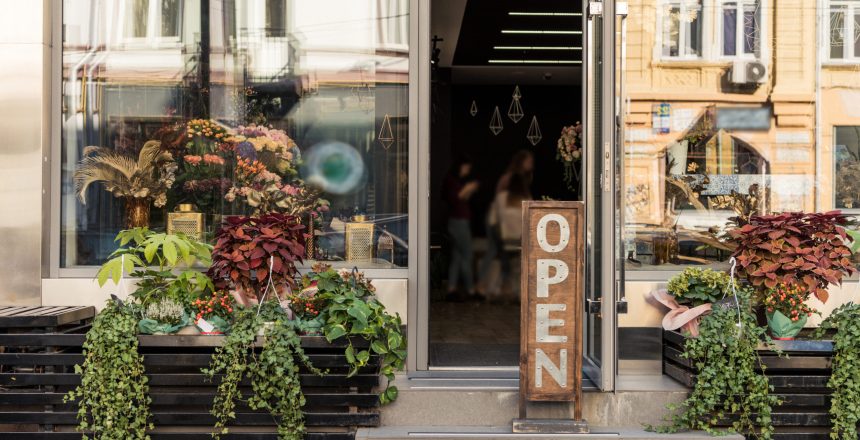 open signboard potted plants and reflecting windows at flower shop
