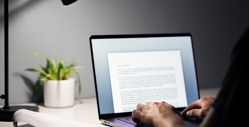 Man writing text document, essay or letter with laptop. Freelance writer, journalist or entrepreneur working late at night, overtime. Job seeker, cv resume and application. Dark home or office room.