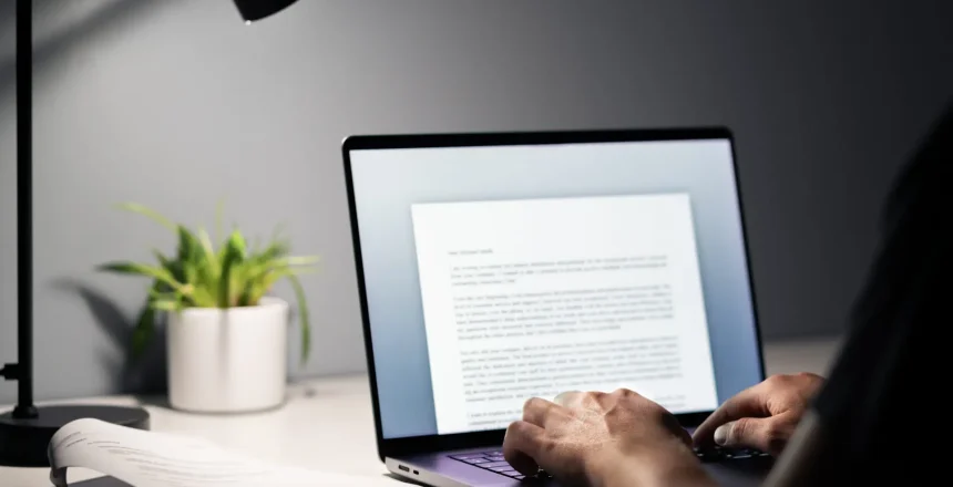 Man writing text document, essay or letter with laptop. Freelance writer, journalist or entrepreneur working late at night, overtime. Job seeker, cv resume and application. Dark home or office room.