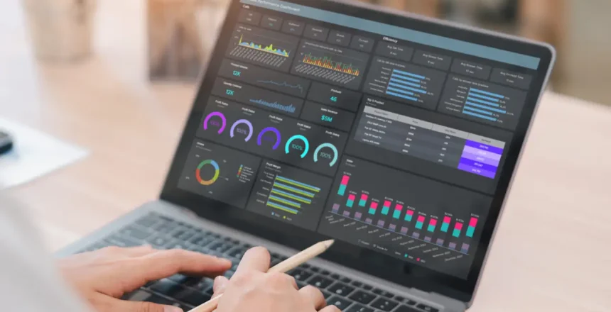 A business professional working on laptop with data analysis dashboard showing graphs and charts, modern office environment, focused and productive atmosphere