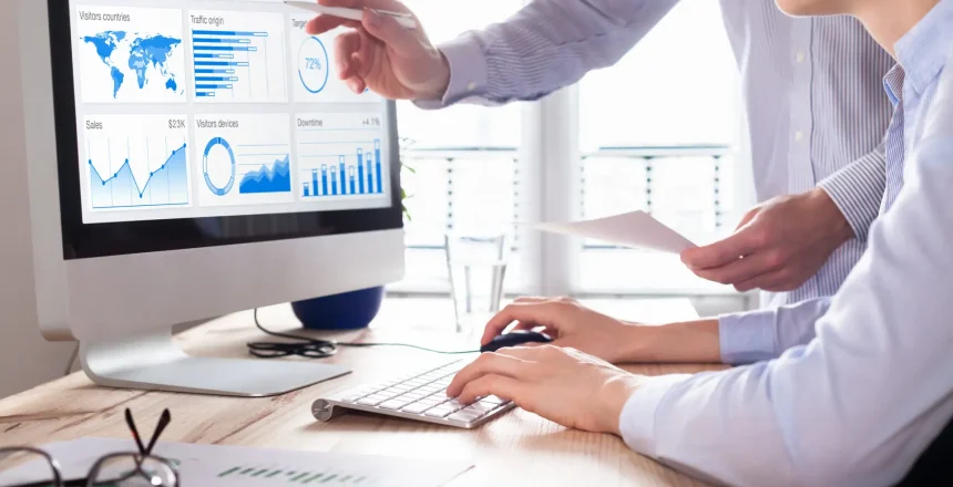 Team of business people discussing digital marketing metrics report and return on investment strategy for advertisement campaign, data analytics dashboard on computer screen in office