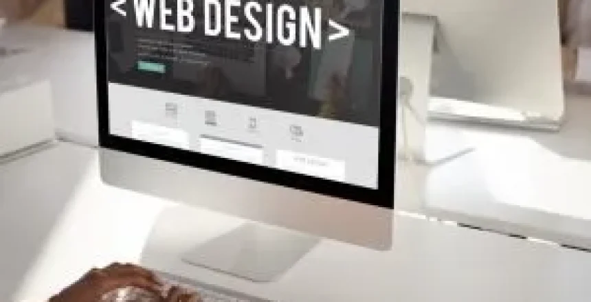 Monitor displaying a web design mockup with the words 'WEB DESIGN' on the screen.